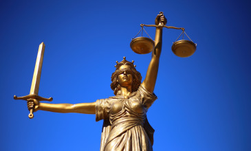 beeld van vrouwe justitia tegen blauwe lucht