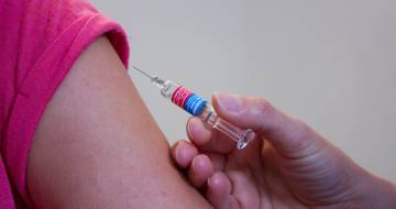 ontblote bovenarm met spuit voor vaccinatie