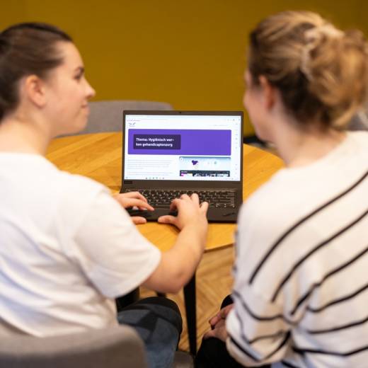 Twee collega's zijn achter een laptop aan de slag met de module hygiënisch werken