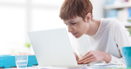 vrouw zit voorovergebogen voor laptop