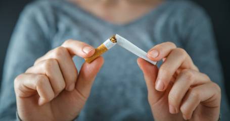 vrouw breekt sigaret in tweeen met handen