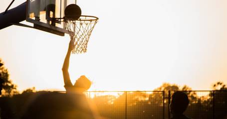 man gooit basketbal in net