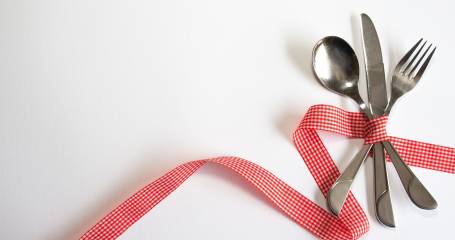 mes vork en lepel bij elkaar gebonden met een rood lint