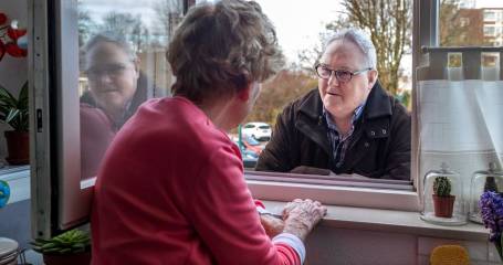 twee personen praten met elkaar in het raamkozijn