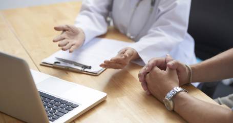 dokter en patient zitten aan tafel