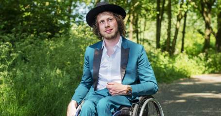 Mari Sanders zittend in zijn rolstoel buiten in het bos