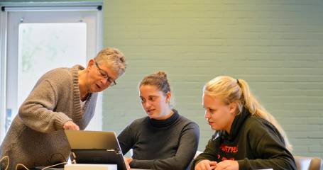 Docent legt theorie uit aan twee studenten 