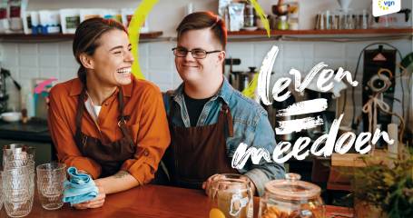 twee mensen aan het werk in een cafe kijken lachend naar elkaar. tekst leven is meedoen