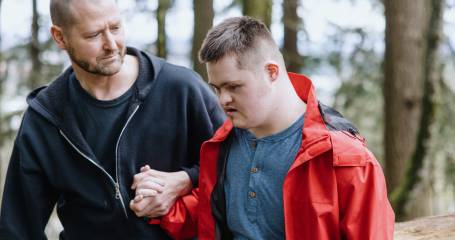 man met beperking die wandelt met begeleider