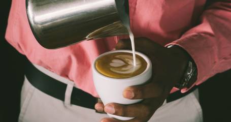 iemand die melk in de koffie schenkt