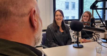 Man van achterkant bezien, in gesprek met twee vrouwen die tegenover hem zitten