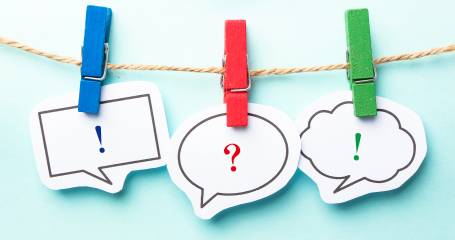 Draad met daaraan knijpers die tekstwolkjes met een uitroepteken en vraagteken vastklemmen