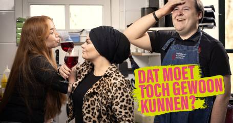 twee vrouwen drinken wijn en een man staat er lachend naast