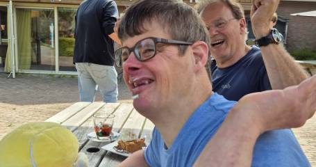 Henk en Jouke zitten lachend en etend aan een picknicktafel