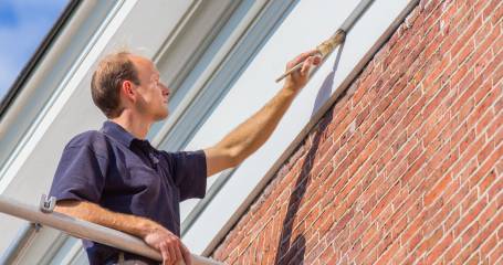 Schilder werkt aan onderhoud huis