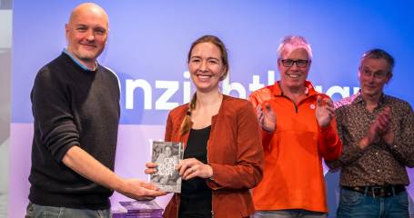 Staatssecretaris Pouw ontvangt het eerste exemplaar van het boek Onzichtbaar uit handen van Boris van der Ham