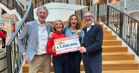 Vier mensen kijken lachend in de camera en houden een checque vast van 35000000 euro van de postcodeloterij