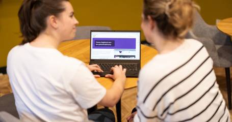 Twee collega's zijn achter een laptop aan de slag met de module hygiënisch werken