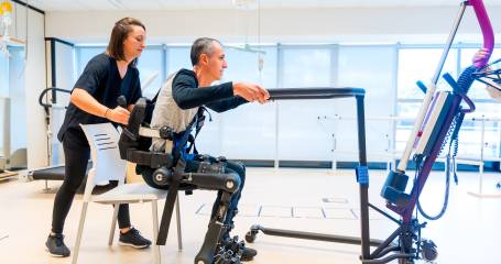 Mechanisch exoskelet. Een fysiotherapeut helpt een persoon met een beperking overeind met behulp van een robotisch skelet. Futuristische revalidatie in een modern ziekenhuis.