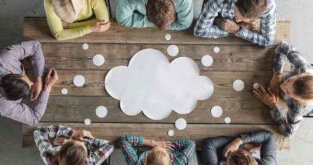 mensen zitten om een tafel met een wolk erop