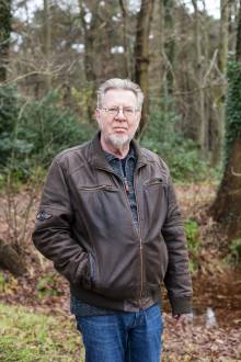 peter siebesma staat buiten in een herfstbos en kijkt in de camera