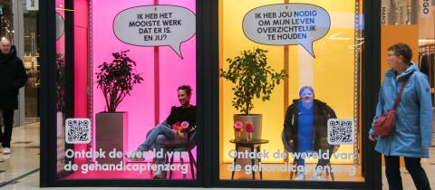 Een roze en oranje etalage met de tekst Ken jij deze kant van Nederland erop en in de etalege zitten twee vrouwen