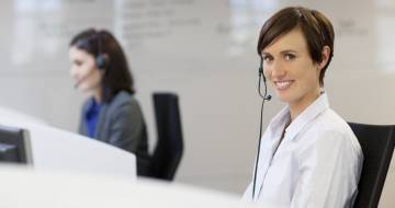 Helpdesk mevrouw met headset achter telefoon