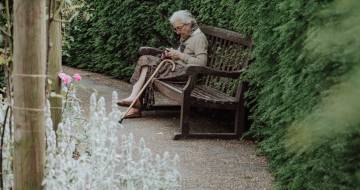 Vrouw in tuin met mobiel