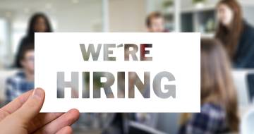 Hand houd bordje omhoog met tekst wer're hiring
