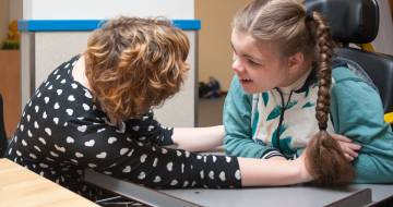 vrouw buigd naar meisje met een beperking