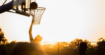 man gooit basketbal in net