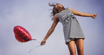 meisje met rode ballon in gestreepte jurk sprint in de lucht 