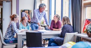 vijf mensen zijn in gesprek met elkaar en lachen
