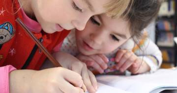 twee kinderen buigen zich over schoolwerk