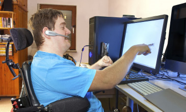Jongen in rolstoel achter computer