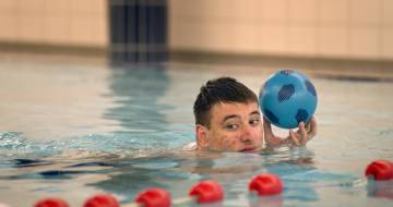 man in zwembad met een bal