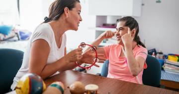 Vrouw met tamboerijn kijkt lachend naar andere vrouw die naar haar hoofd wijst