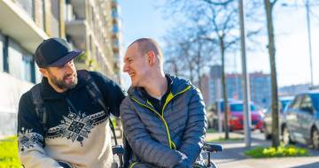 Man in een rolstoel met begeleider