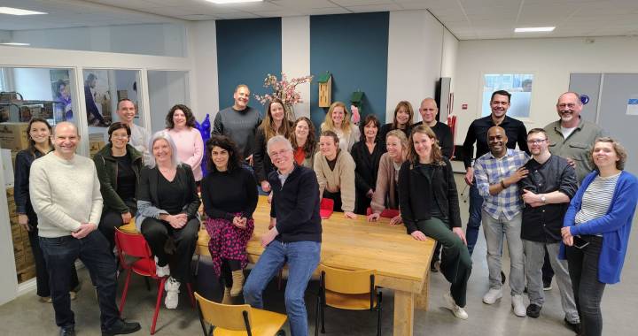 Groep mensen kijkt lachend in de camera