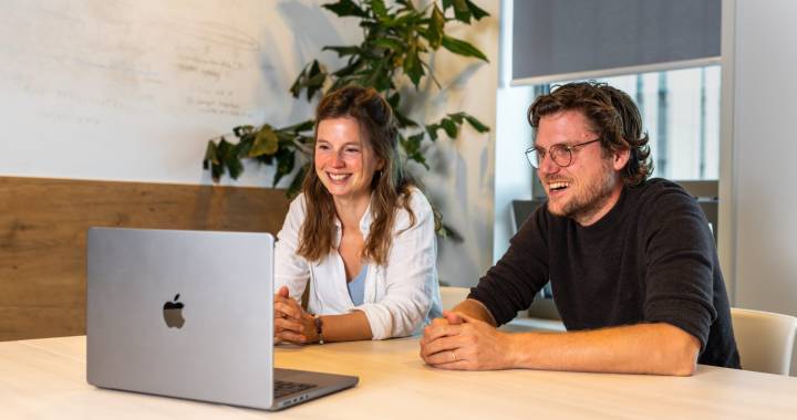 Twee personen achter een laptop die een webinar volgen