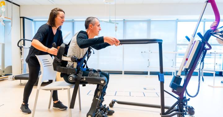 Mechanisch exoskelet. Een fysiotherapeut helpt een persoon met een beperking overeind met behulp van een robotisch skelet. Futuristische revalidatie in een modern ziekenhuis.