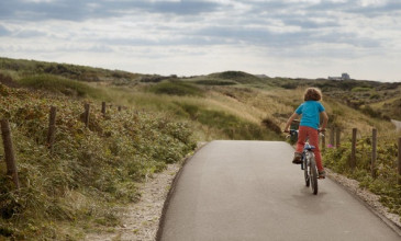 jongetje op fiets fietst door de duinen