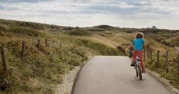 jongetje op fiets fietst door de duinen