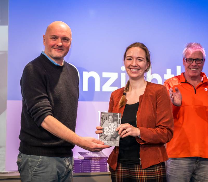Staatssecretaris Pouw ontvangt het eerste exemplaar van het boek Onzichtbaar uit handen van Boris van der Ham