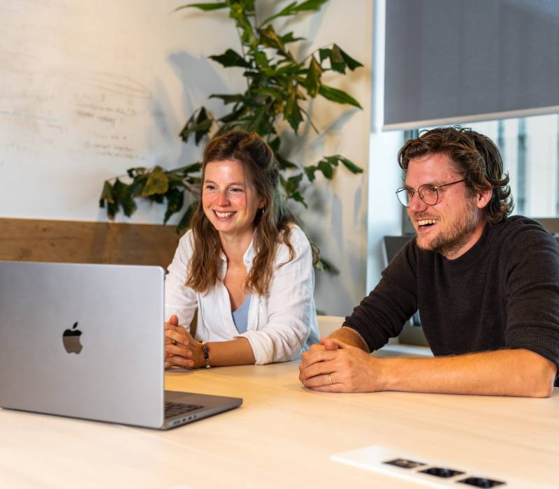 Twee personen achter een laptop die een webinar volgen