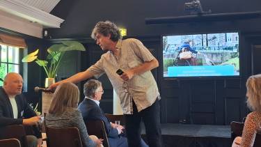 Pieter hilhorst staan tussen een zitten publiek en houdt microfoon onder de neus van Boris van der Ham