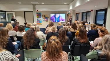 groep mensen zit in een zaal naar een filmpje te kijken