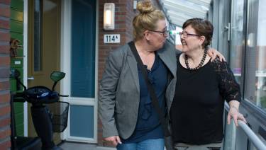 Begeleidster loopt buiten met arm om cliënt