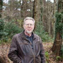 peter siebesma staat buiten in een herfstbos en kijkt in de camera