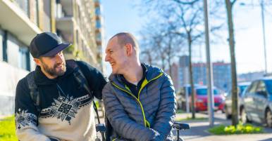 Man in een rolstoel met begeleider